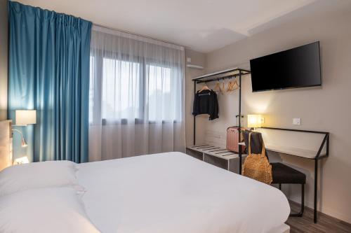 EstillacThe Originals City, Relais d'Estillac, Agen Sud的酒店客房配有一张床和一张书桌及一台电视