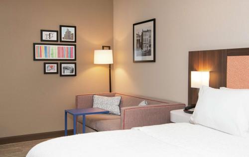 伊利Hampton Inn Erie-South的配有一张床和一把椅子的酒店客房