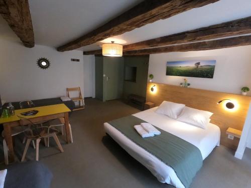拉吉约勒La Maison - Hôtel & Gîte的一间卧室配有一张床、一张桌子和一张桌子