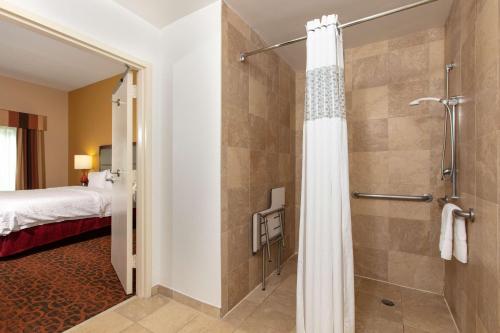 杰克逊维尔杰克逊维尔机场汉普顿套房酒店的一间带步入式淋浴间的浴室和一张床