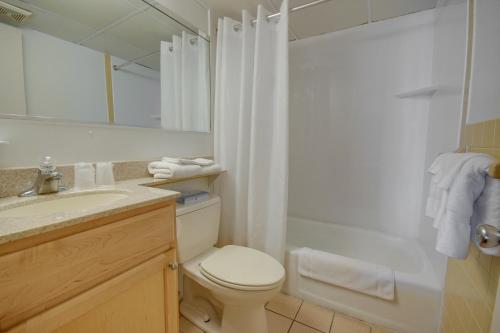 大洋城火烈鸟汽车旅馆的一间带卫生间、水槽和镜子的浴室