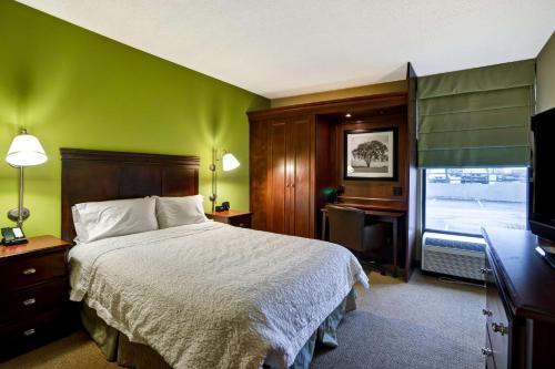 摩根敦汉普顿摩根酒店的一间卧室配有一张床、一张书桌和一台电视