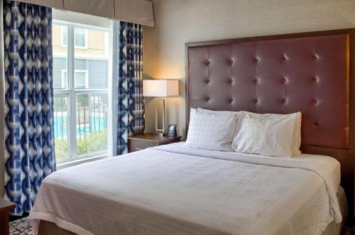 莫比尔摩拜尔希尔顿惠庭套房酒店的一间卧室设有一张大床和大窗户