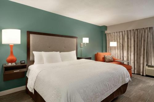 新奥尔良新奥尔良/圣查尔斯大道汉普顿酒店的酒店客房带一张大床和一把椅子