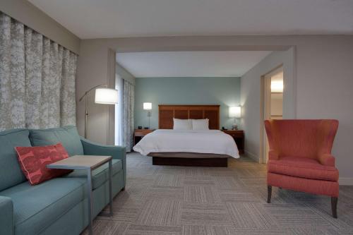 默特尔比奇哈伯盖特汉普顿酒店的一间卧室配有一张床、一张沙发和一把椅子