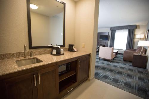俄克拉何马城俄克拉何马城机场汉普顿酒店及套房的一间带水槽和镜子的浴室和一间客厅