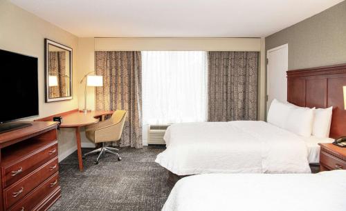 帕西帕尼汉普顿帕西帕尼酒店的酒店客房设有两张床、一张桌子和一台电视。