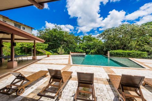 普拉卡海尔Jobo 8 Luxury Apartment - Reserva Conchal的一个带椅子的庭院和一个游泳池