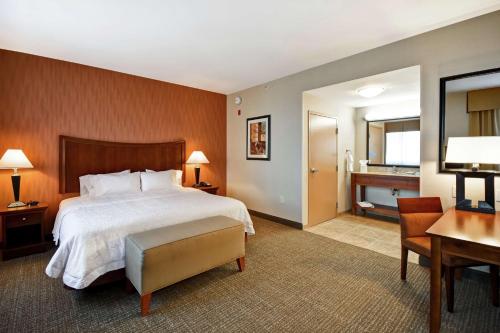 佛森福尔瑟姆希尔顿恒庭旅馆&套房酒店的酒店客房设有一张大床、一张书桌和一张书桌。