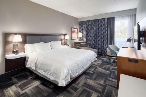 路易斯威尔路易斯维尔东北汉普顿酒店的酒店客房设有一张大床和一张书桌。