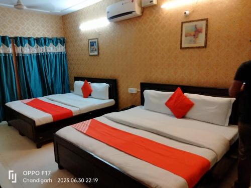 钱德加尔Hotel Diamond Ring Chandigarh的酒店客房带两张带红白色枕头的床