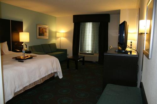 什里夫波特什里夫波特机场汉普顿旅馆的酒店客房配有床、沙发和电视。
