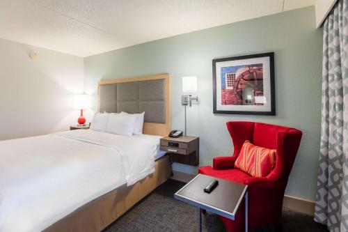 圣查尔斯Hampton Inn St Charles St Peters的酒店客房,配有一张床和一张红色椅子