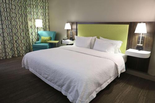 萨姆特萨姆特汉普顿酒店的酒店客房带一张大床和一把椅子