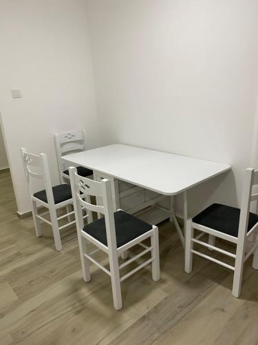 尼克希奇Apartman Oaza的白色的桌椅、白色的桌子和四把椅子