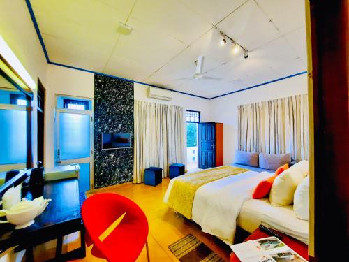 尼甘布道尔斯特酒店的一间卧室配有一张大床和一张红色椅子