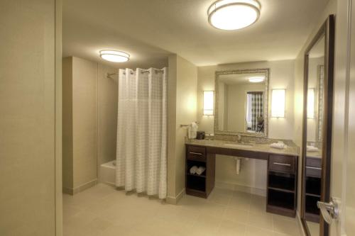 维多利亚维多利亚希尔顿惠庭套房酒店的浴室配有淋浴帘和盥洗盆。