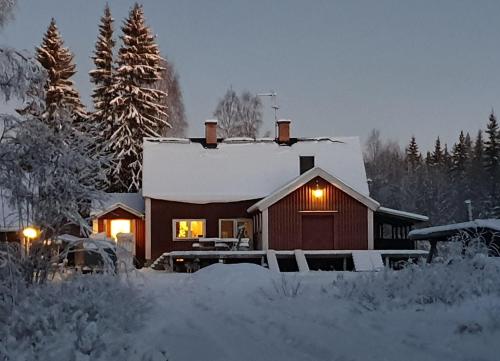 SörsjönStationshuset Dalarna Apartments的雪覆盖着的房屋,里面装着灯