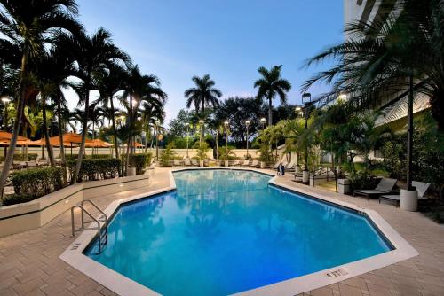 布卡拉顿博卡拉顿大使套房酒店的度假村内一座种有棕榈树的大型游泳池