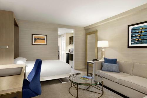 波士顿波士顿-剑桥希尔顿逸林酒店的酒店客房配有床、沙发和桌子。