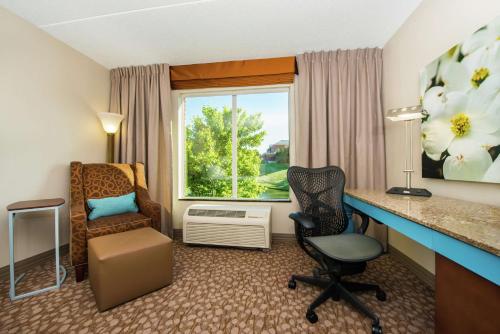 夏洛茨维尔夏洛茨维尔希尔顿花园旅馆的酒店客房设有一张桌子、一把椅子和一个窗户。