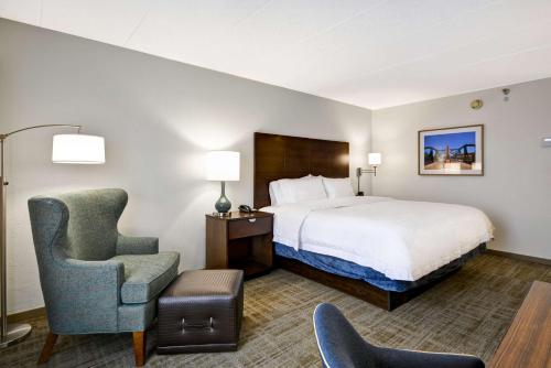 内珀维尔芝加哥纳珀维尔希尔顿恒庭酒店的配有一张床和一把椅子的酒店客房