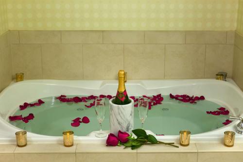 梅菲尔德东克利夫兰/梅菲尔德村希尔顿花园酒店的浴缸配有1瓶香槟和2杯葡萄酒