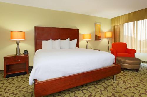 哥伦布希尔顿花园酒店哥伦布机场店的酒店客房设有一张大床和一张红色椅子。
