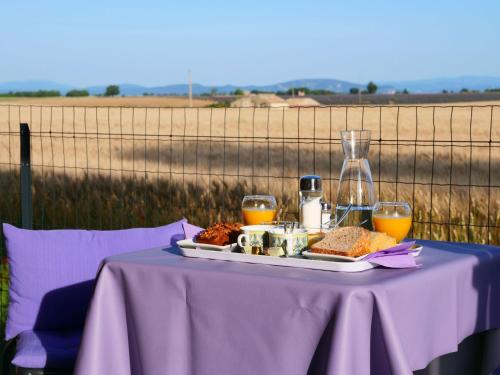瓦朗索尔Le Spa des lavandes的紫色桌子,盘子上放着食物和橙汁