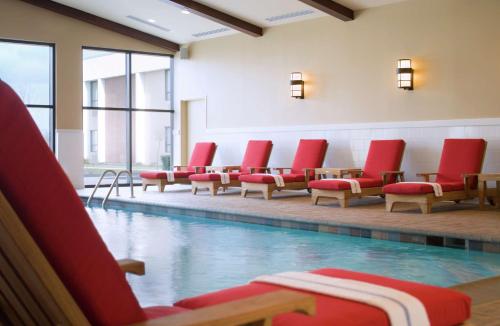 希布伦辛辛那提机场希尔顿逸林酒店的一座带红色椅子的游泳池