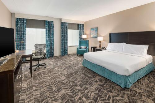 银泉Hilton Garden Inn Silver Spring White Oak的酒店客房配有一张床、一张书桌和一台电视。