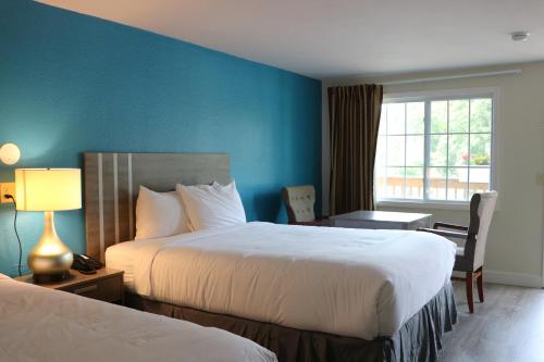 西雅茅斯Sunbird Cape Cod Resort的酒店客房设有两张床、一张书桌和一个窗户。