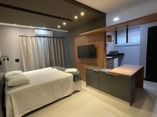 里梅拉Globo Lar Studios的一间卧室配有一张床、一张书桌和一台电视