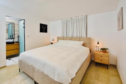 H̱azonאדמת הארץ - Admat Haaretz的卧室配有一张白色大床和镜子