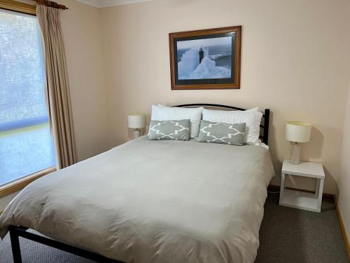 罗布Cosy On Tobruk的卧室配有带枕头的床铺和窗户。