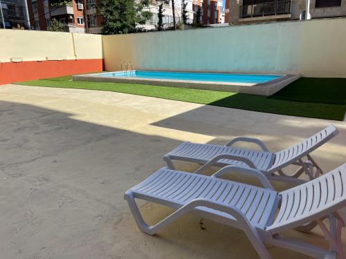马德里BEST FLAT NEAR REAL MADRID STADIUM的两个白色长椅,位于游泳池旁