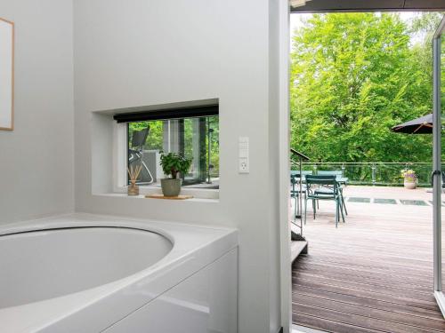 埃贝尔托夫特8 person holiday home in Ebeltoft的带浴缸的白色浴室和庭院。