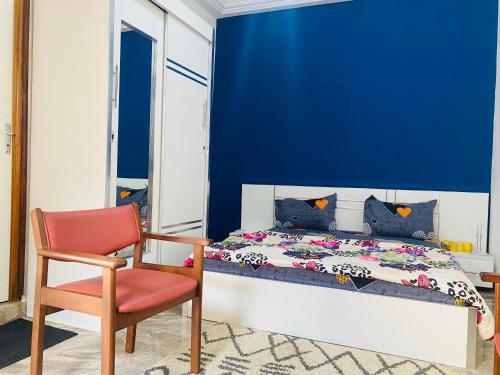 达喀尔RESIDENCE EL HADJI的蓝色卧室,配有床和红色椅子