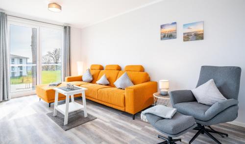 加兹尤瑟多姆Apartment "Sanddorn" - Haffresidenz的客厅配有橙色沙发和两把椅子