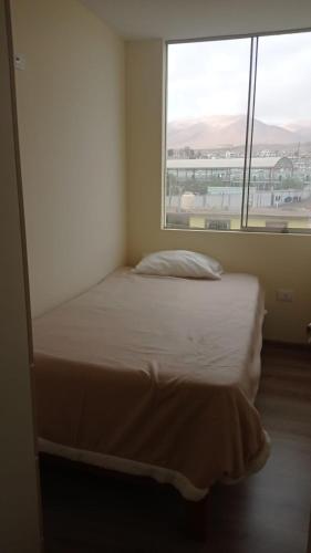 伊洛Apartamento Costa Ilo的一张位于带大窗户的房间内的床铺