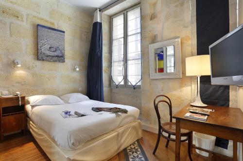 波尔多Hôtel La Tour Intendance的一间卧室配有一张床、一张书桌和一台电视