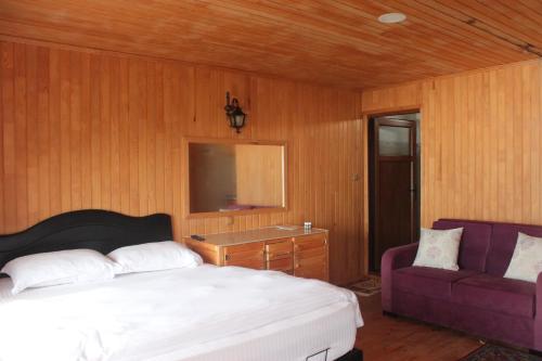 ÇaykaraSultanmurat AymeydanıTatil Köyü的一间卧室配有一张床和一张紫色沙发