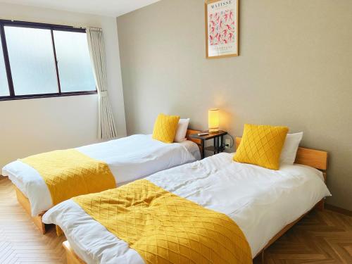 大阪Modern and Traditional Fusion Villa in Umeda 3-Min Walk to Subway Ideal for Families and Groups的两张睡床彼此相邻,位于一个房间里