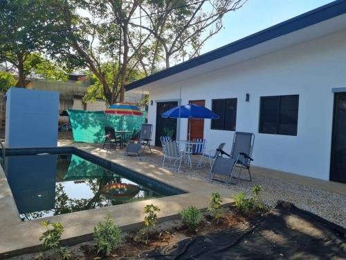 塔马林多Casa Mar de Sueños Tamarindo的一座带游泳池、椅子和遮阳伞的房子