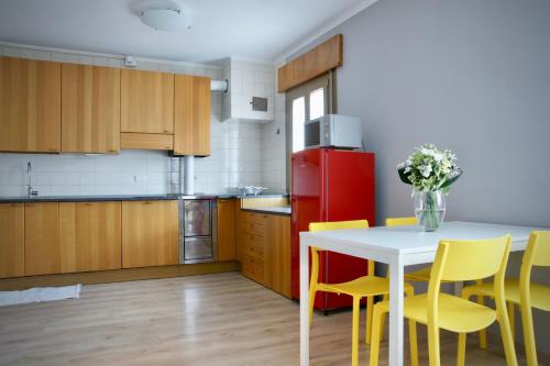布亚B&B The Secret Garden的厨房配有桌子、黄色椅子和红色冰箱