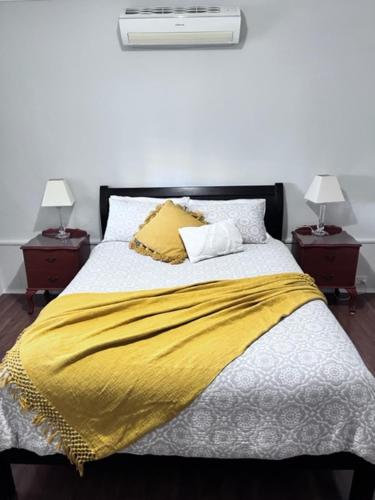 阿德莱德Penzance Cottage的一张带黄色毯子和2个床头柜的床