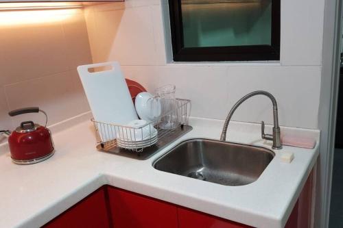 新山Sky Loft 3 rooms beside Aeon With Smart TV & Facilities L14的一个带水槽和红色橱柜的厨房台面