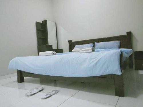 新山Sky Loft 3 rooms beside Aeon With Smart TV & Facilities L14的一间卧室配有一张带蓝色床单和拖鞋的床。