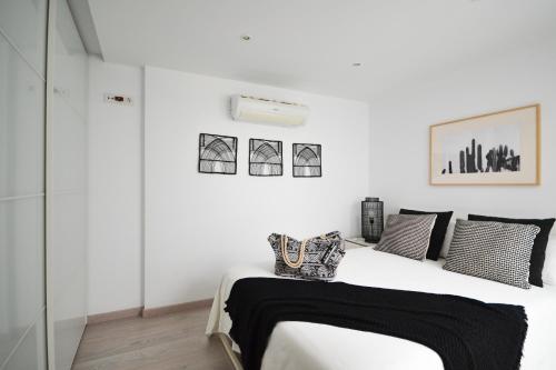阿吉内金海滩Luminoso loft recién reformado的白色卧室配有带黑白枕头的床