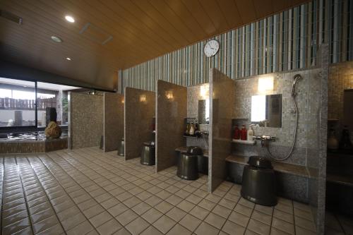大分多美迎大分酒店的一间设有摊位和墙上时钟的公共浴室